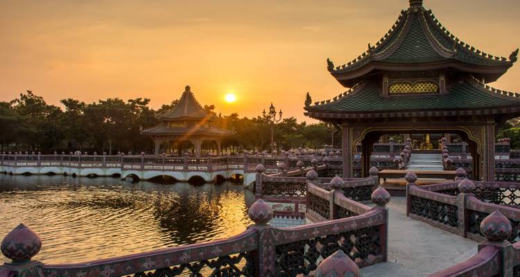 Des pavillons lakeside ornés et des allées sinueuses illuminés au coucher du soleil au-dessus d'une eau calme.