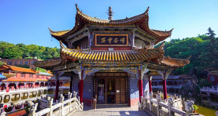 Temple historique coloré de Yuantong avec des toits aux tuiles complexes enjambant un petit pont.