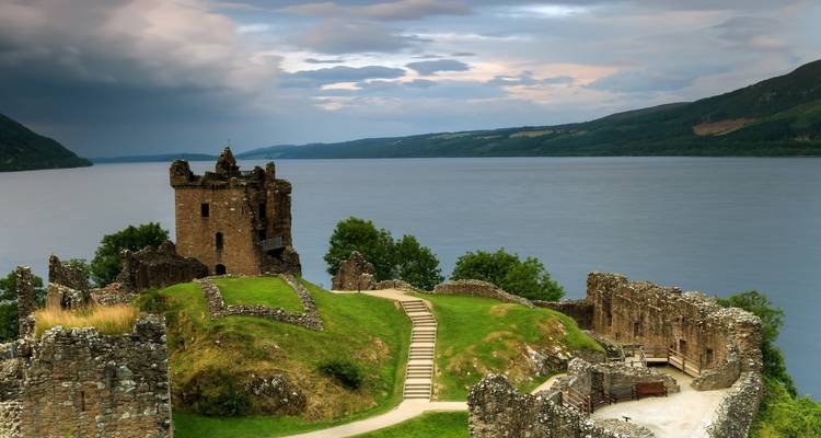 Ruins of Urquhart Castle overlooking the expansive waters of Loch Ness under moody skies.