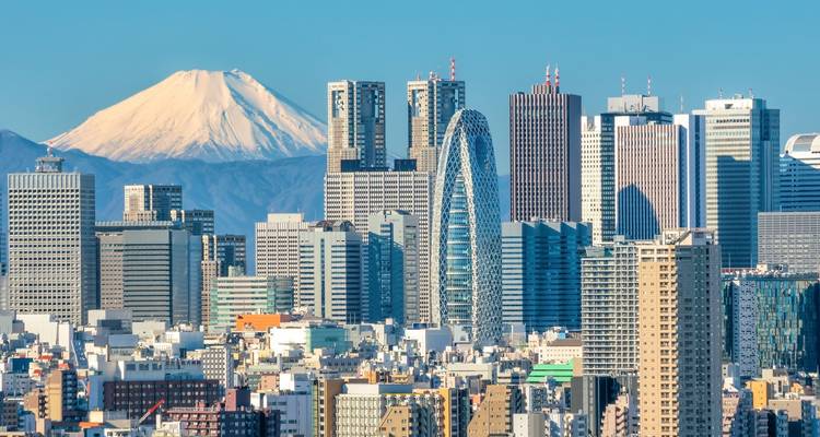 Tokyo skyscraper skyline framed by snow-capped Mount Fuji on a clear day.