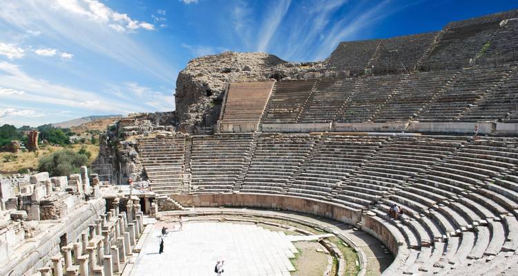 Well-preserved ancient Roman theater with stone seating tiers curving around a central stage under vivid sky