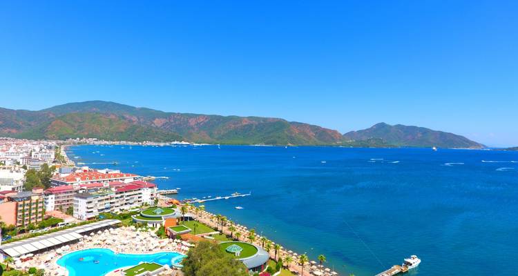 Resort coastline of Marmaris with hotels, pools, and deep blue bay framed by forested mountains