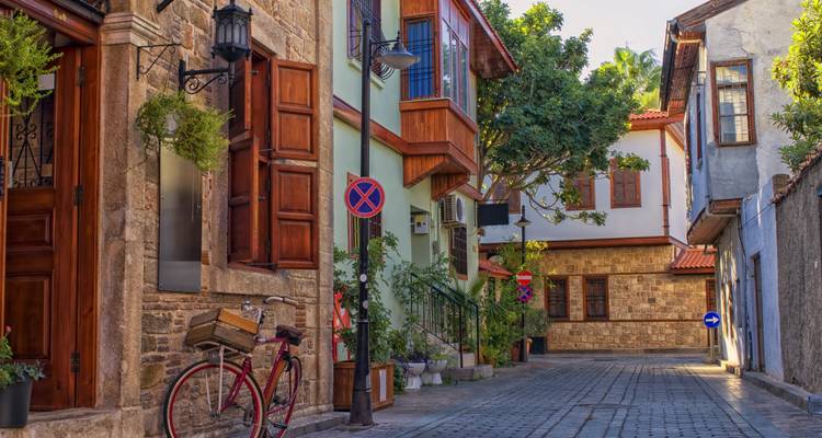 Quiet cobblestone street lined with restored Ottoman houses, bicycle and greenery