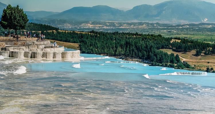 Visitors admire the expansive Pamukkale terraces overlooking forested plains and distant mountains