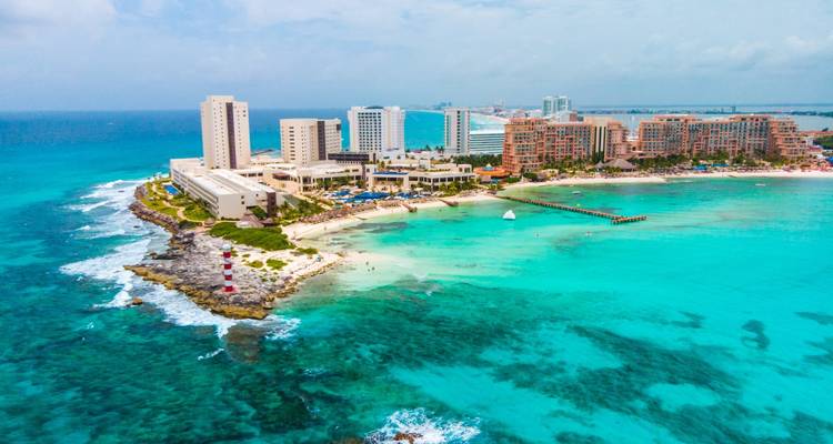 Aerial of Cancun hotel zone jutting into turquoise Caribbean Sea with white sand beaches and resorts.