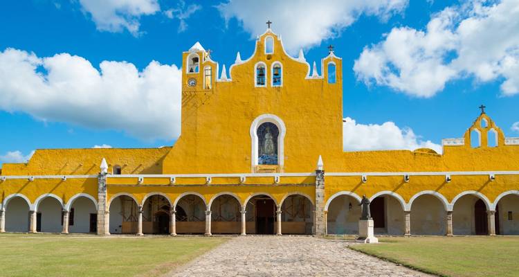 Bright yellow Convent of San Antonio de Padua with white arches set against blue sky in Izamal.