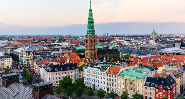 Panorama urbain de Copenhague mettant en évidence la flèche verte de l'église Saint-Nicolas au-dessus des toits colorés.