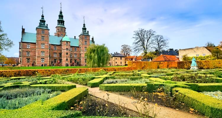 Château de Rosenborg avec des jardins de haies soignés affichant les couleurs d'automne sous un ciel dégagé à Copenhague.