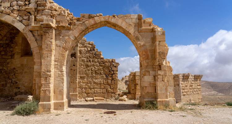 Portique en pierre usée et ruines d'un château des Croisés par une journée ensoleillée.