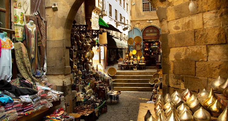 Ruelle de marché animée dans le bazar historique du Caire remplie de lampes en laiton, de tissus et de souvenirs traditionnels.