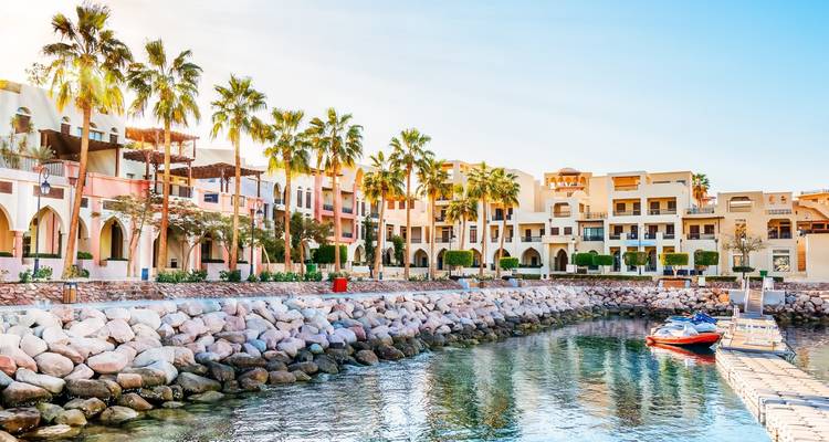 Colorful seaside resort architecture and palm-lined promenade along calm waters in Aqaba.