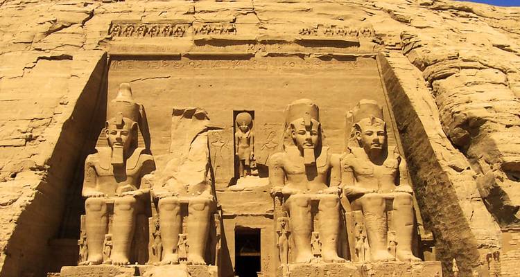 Façade ensoleillée du temple principal d'Abu Simbel avec des statues colossales et des hiéroglyphes.