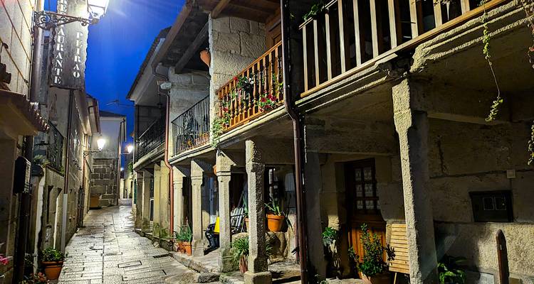 Ruelle en pierre de charme avec balcons et pots de fleurs illuminés la nuit