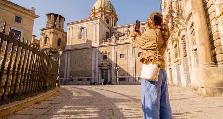 Female traveler photographing a grand baroque dome and historic church façade under clear sky