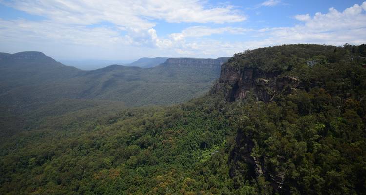 Expansive forested ridges roll into the distance beneath a bright sky.