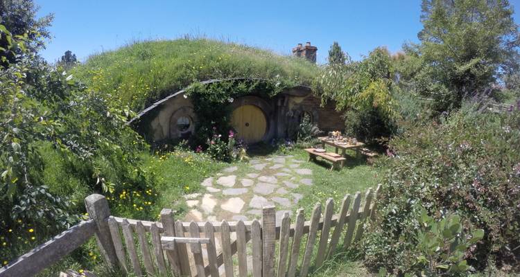 Picket fence and wildflower garden in front of a hobbit house with a round yellow door.