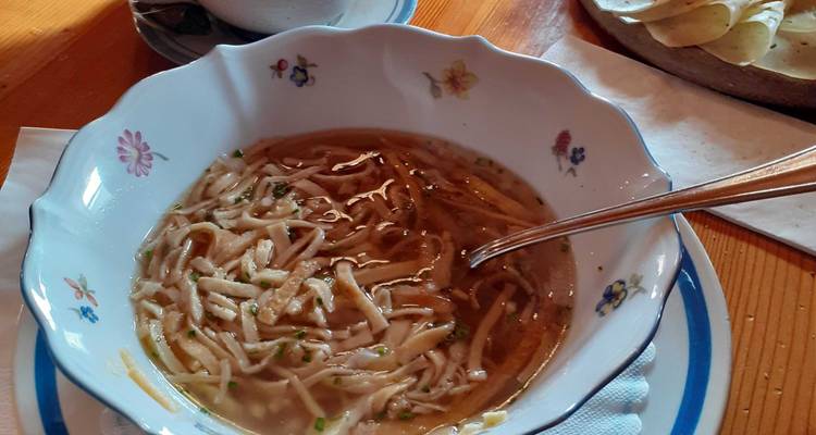 Gros plan d'une soupe de nouilles traditionnelle servie dans un bol en porcelaine à motifs floraux sur une table en bois.