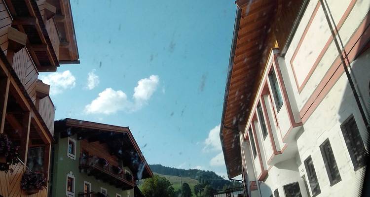 Vue de rue à travers une vitre de véhicule tachetée de pluie regardant vers le haut les maisons du village alpin.