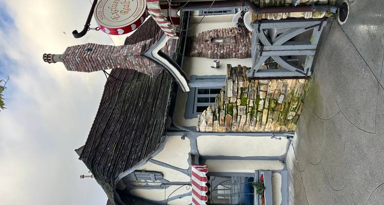 Storybook cottage with half-timbered walls, striped awnings and rustic stone chimney.