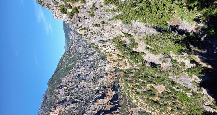 Rugged canyon walls and jagged ridges stretch into the distance under bright blue skies.