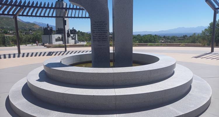 Granite circular memorial fountain overlooking a valley and distant hazy mountains.
