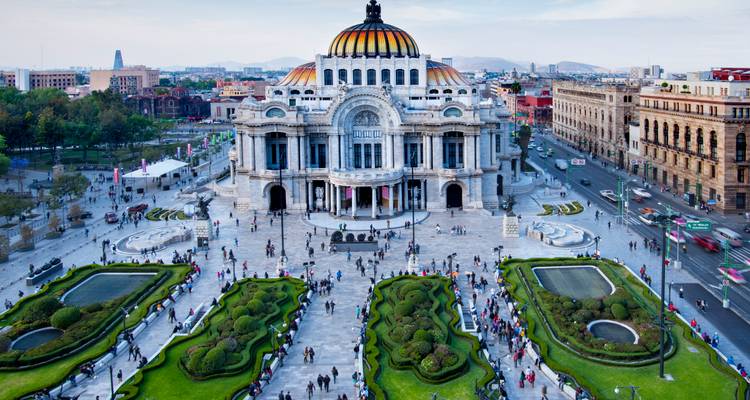 Grand Palacio de Bellas Artes in Mexico City surrounded by manicured gardens and bustling crowds.