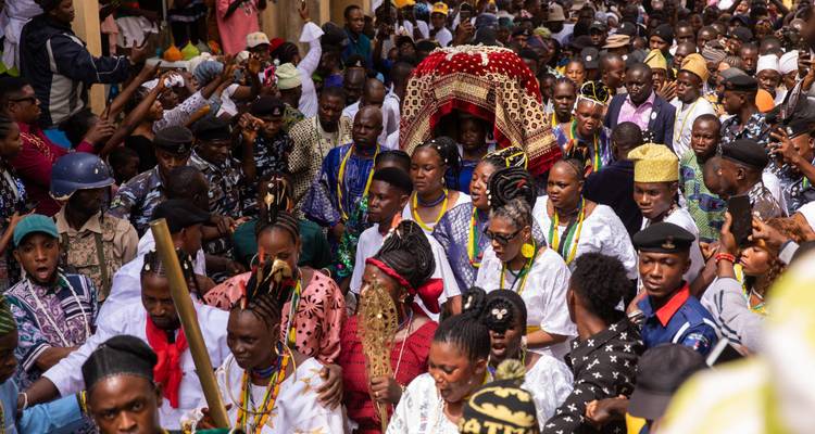 Colorful Yoruba festival procession with drummers, dancers and crowds in vibrant attire.