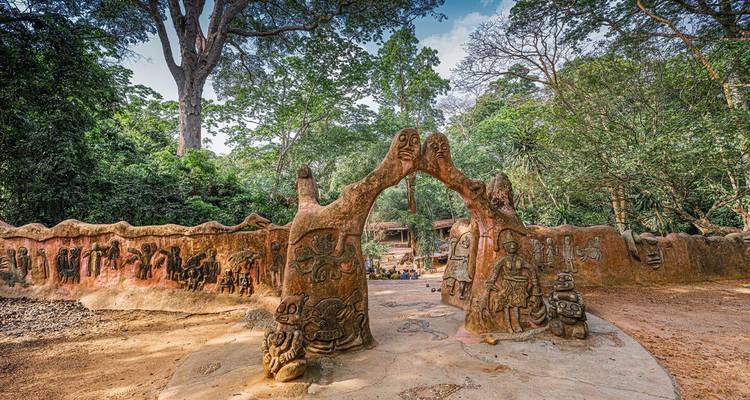 Clay sculpture wall with symbolic figures in a sacred forest setting, Osogbo.