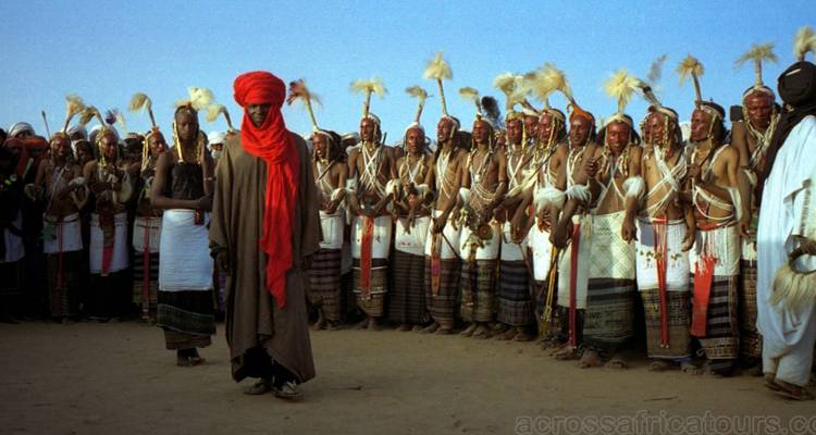 Gran fila de bailarines Wodaabe en trajes tradicionales durante el festival Gerewol en el desierto.