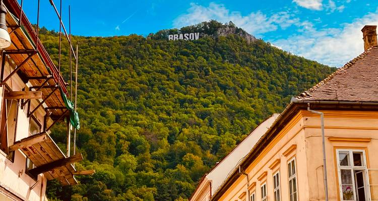 Vue jusqu'à la montagne couverte de forêts avec le panneau blanc audacieux BRASOV au-dessus des toits de la vieille ville