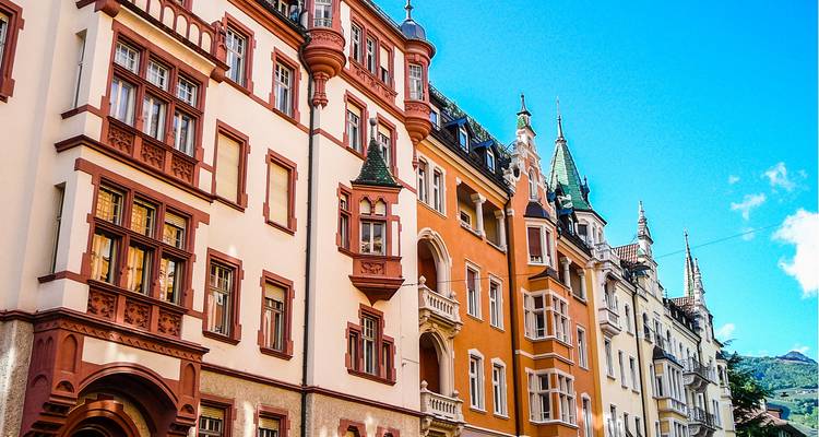 Des maisons de ville historiques aux couleurs vives, dotées de fenêtres ornées et de tourelles, sous un ciel bleu dégagé.