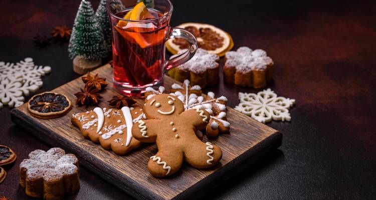 Biscuits au pain d'épices avec un verre de vin chaud et des décorations festives sur une planche en bois.