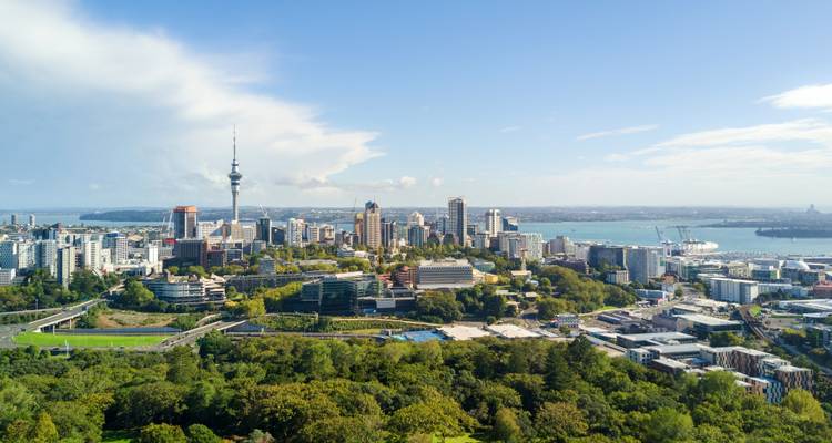 Aerial panorama of Auckland city centre and harbor backed by a bright blue sky.