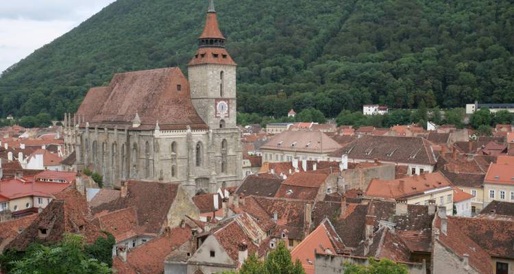 Rooftop panorama of Brasov old town with Black Church beside a forested hill