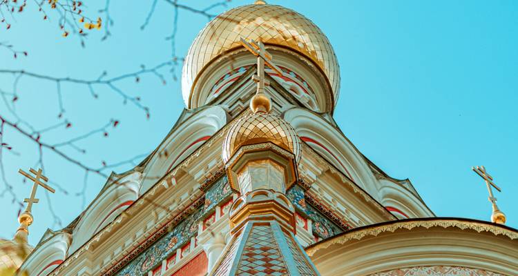 Close-up of ornate golden onion domes of an Eastern Orthodox church against blue sky