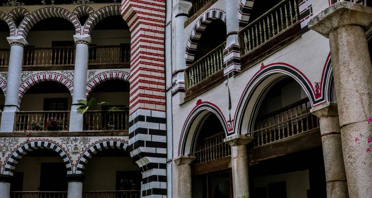 Arcaded interior courtyard of a monastery featuring striped arches and balconies