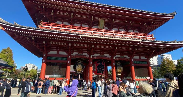 Large red gate of Senso-ji Temple bustling with crowds on a sunny day