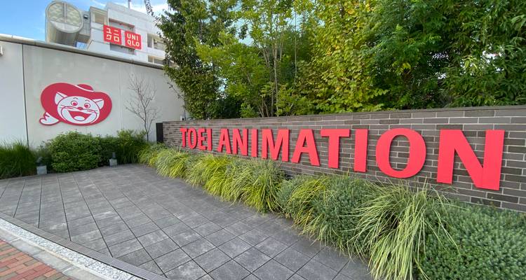 Brick wall sign for Toei Animation studio with greenery and pavement