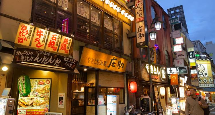Narrow alley of restaurants and bars glowing with neon signage at dusk