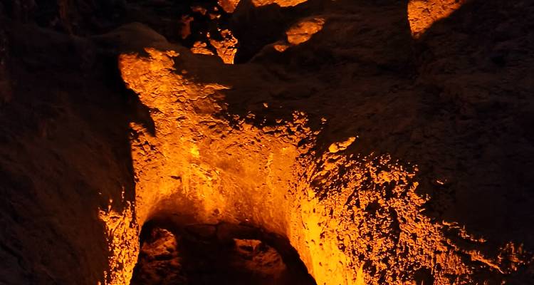Paroi du tunnel volcanique illuminée rougeoyant d'orange en raison de la chaleur souterraine.