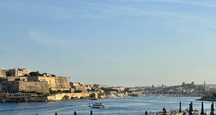 Coastal fortifications and a boat cruising through Malta’s Grand Harbour.
