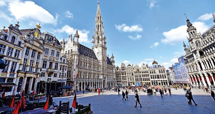Der Große Platz in Brüssel mit kunstvollen Zunfthausfassaden und dem hohen gotischen Rathaus unter blauem Himmel.