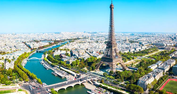 Luftaufnahme von Paris mit dem Eiffelturm, der Seine und der sich ausbreitenden Stadtlandschaft an einem klaren Tag.