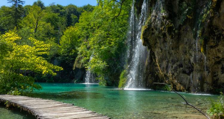 Piscine turquoise cristalline et cascades en cascade le long d'une promenade en bois aux lacs de Plitvice.