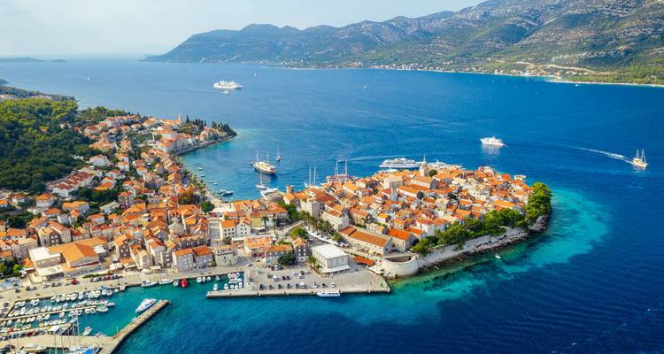 Vue aérienne colorée de la péninsule de la vieille ville de Korčula entourée par les eaux turquoises de la mer Adriatique et des bateaux.