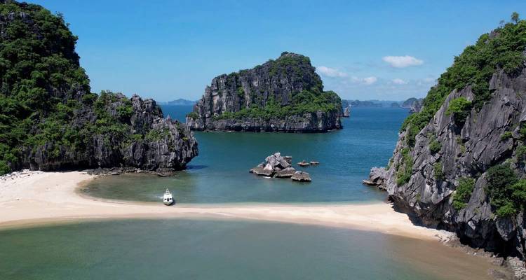 Unberührter Strand und smaragdgrüne Kalksteinkarstberge der Ha-Long-Bucht unter blauem Himmel