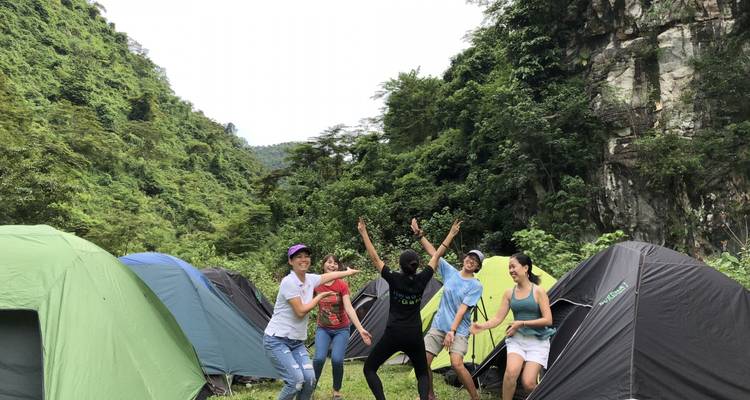 Cheerful campers jump and pose between colorful tents in a lush valley