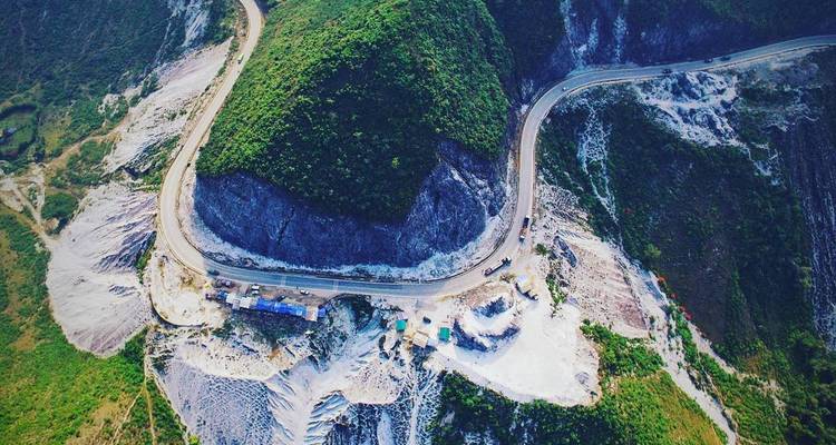 Aerial view of a winding mountain road hugging steep green slopes