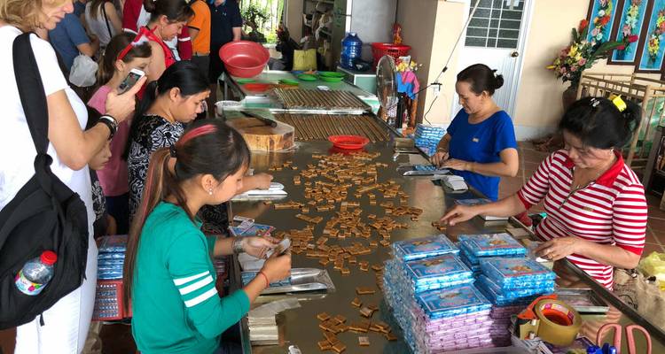 Workers hand-crafting coconut candies at long tables inside a small factory