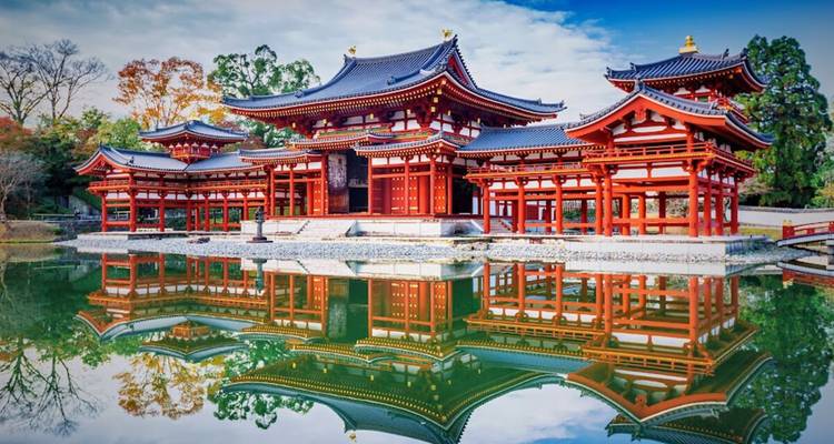 Les halls d'un rouge éclatant du temple Byodo-in se reflètent parfaitement dans un étang tranquille entouré du feuillage automnal de Kyoto.